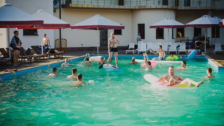 Zaporozhye, Ukraine-August 2018: a pool party in the company of ovoh. funny friends playing volleyball on inflatable boats in the pool in a ride on wakeboarding.のeditorial素材