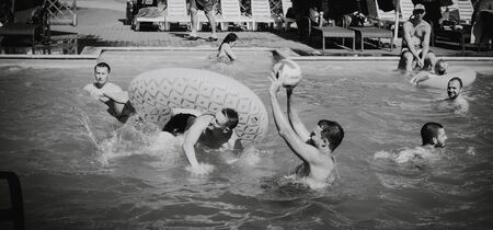 Zaporozhye, Ukraine-August 2018: a pool party in the company of ovoh. Happy friends playing volleyball on inflatable boats in the pool water. black-whiteのeditorial素材