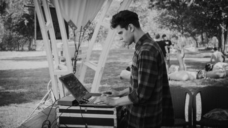 Zaporizhia, Ukraine-August 2018: a pool party in the company ovoh. DJ is focused and picks up music, the concept of music and lifestyle, a focused person with a laptop.black-whiteのeditorial素材