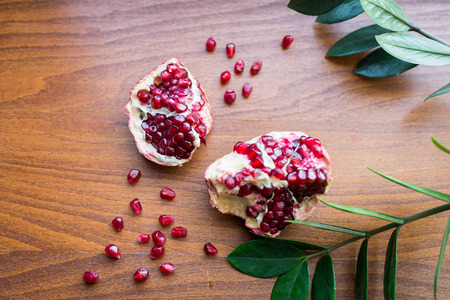 Fresh ripe pomegranate on a wooden table with green leafsの写真素材
