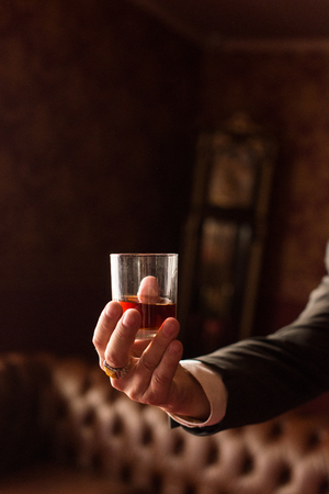 Groom holds in his hand a glass of whiskey indoorsの写真素材