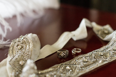 Silver wedding rings on a wooden background with white ribbon with bright stones.の写真素材