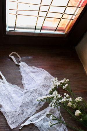 White flowers and white women's lingerie on the wooden windowsillの写真素材