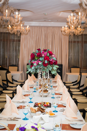 Wedding arrangement with fresh red roses, orchids and eucalyptus on the banquet tableのeditorial素材