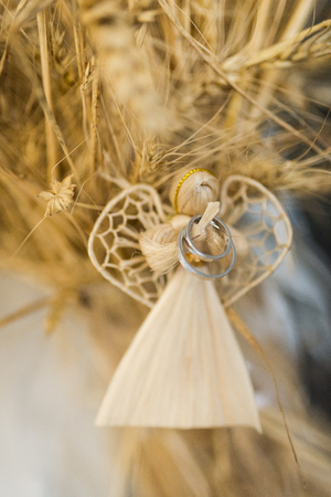 Wedding silver rings hanging on a handmade angel of strawの写真素材