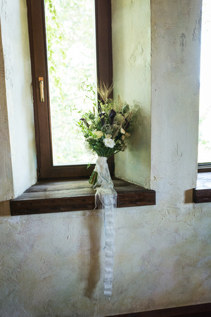 Wedding bouquet with white flowers and greenery on a wooden windowsillの写真素材