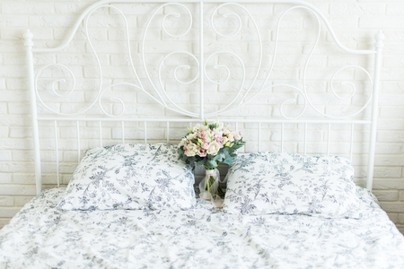 Wedding bouquet with white and pink tulips and pink small roses on a bridal bed with black and white bedclothes on a brick backgroundの写真素材
