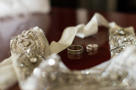 Silver wedding rings on a wooden background with white ribbon with bright stones.の写真素材