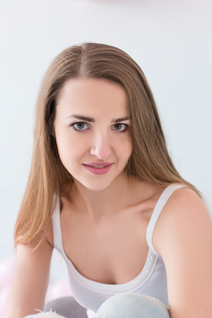 Beautiful young model with long brown hair looking at camera. Natural beauty portrait of woman on whiteの写真素材