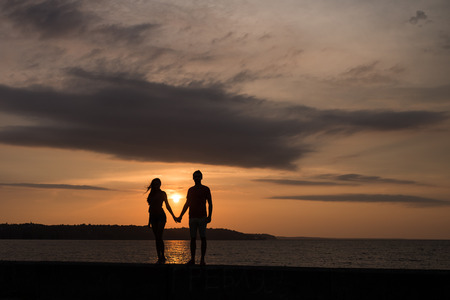 Silhouette of the couple in love in front of a sunsetの写真素材