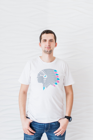 Young smiling man in white T-shirt and blue jeans on a white background looking at cameraの写真素材
