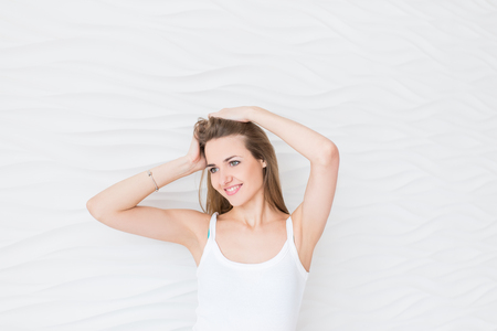 Portrait of a young woman. Smiling, happy. Pretty girl portrait adjusting her long hair with her handの写真素材