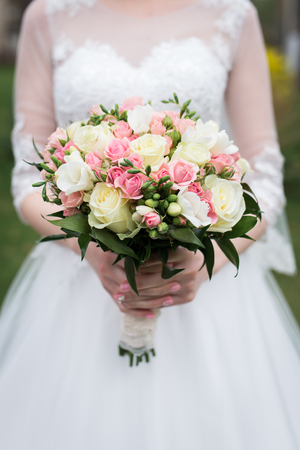 Bridal bouquet with white and pink roses. Wedding. The bride in white wedding dress holds a wedding bouquet with white and pink roses, greenery.の写真素材