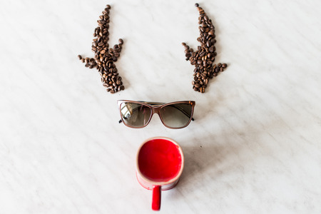 Deer. Horns from coffee beans. Sunglasses. Red cupの写真素材