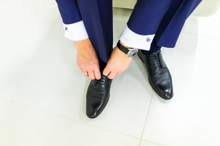 Groom wearing shoes on wedding day, tying the laces and preparing. Business man dressing up with elegant shoes.の写真素材