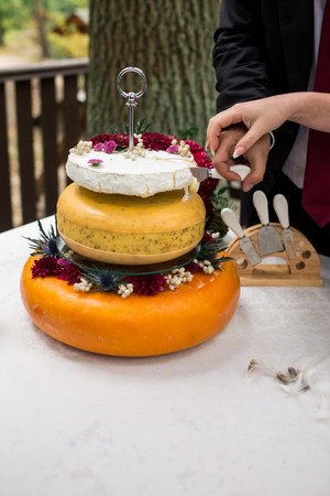 Salt wedding cake from cheese. Three cheese heads as a wedding cake. Newlyweds cutting a wedding cheese cakeの写真素材