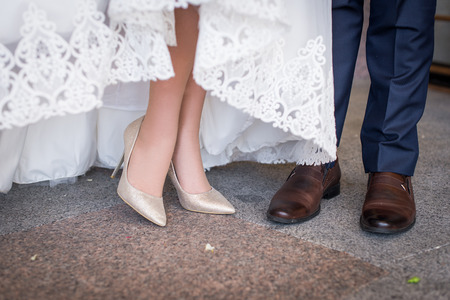 Legs and feet of married couple in stylish shoes. Women's high heel shoes and men's brown shoesの写真素材