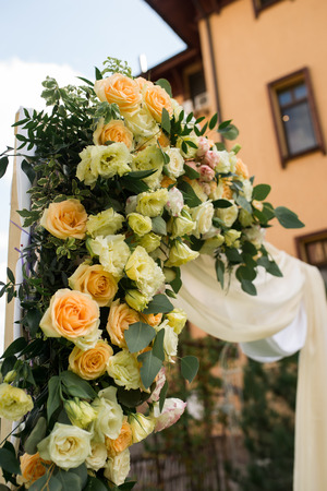 Closeup of beautiful wedding arch with fresh flowers in beige colors in the gardenの写真素材
