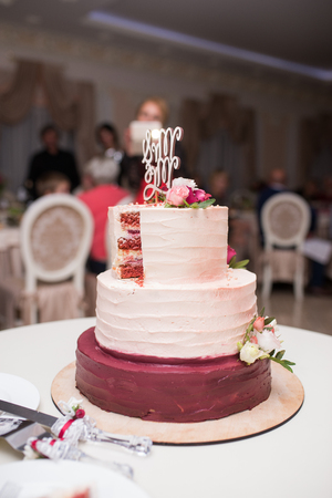 White and red tree-tier wedding cake with fresh flowers on the tableの写真素材