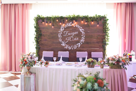 Interior of newlyweds table in restaurant in rustic style with natural decor: fresh flowers and retro garlands.の写真素材