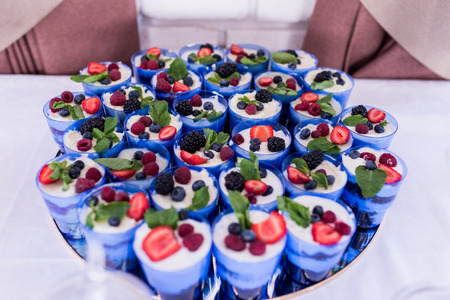 Trifle. A lot of trifles or cake in a blue glasses decorated with berries. Festive layered dessert in glass.の写真素材