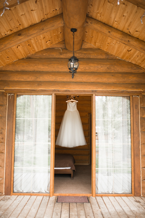White lush wedding dress hanging on the hanger in the room view from the street. Bridal gown.の写真素材