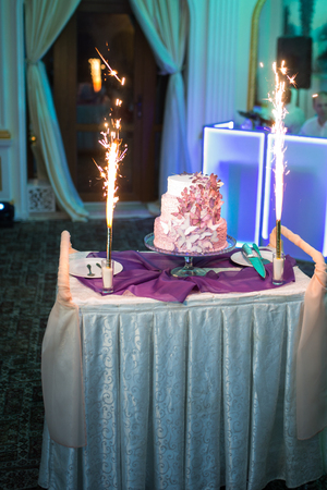 The wedding cake with fireworks stand on the table in restaurantの写真素材