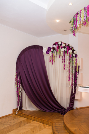 Wedding arch in the shape of a heart decorated with purple and white material and flowers. Floral archway at a wedding ceremony.の写真素材