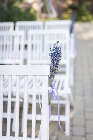 Lavender flowers. Backrest of a chair decorated with a bouquet of lavender. Wedding chair decorated with a lavender flower. Wedding detailsの写真素材