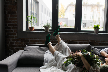 Girl's bride's legs in green elf style shoes on the sofa. The bride's legs in green stylish shoesの写真素材