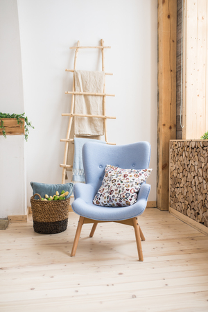 Interior of Scandinavian room. Blue armchair with a pillow on them, a wooden staircase with a towel hanging on it, basket with tulips. Homeの写真素材
