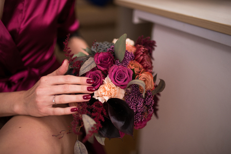 Beautiful wedding bouquet in hands of the bride. Trendy and modern wedding flowers in marsala colors. Prepare for the wedding.の写真素材