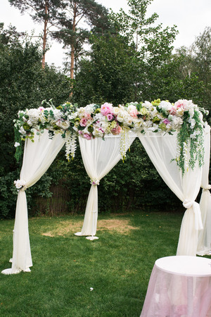 The beautiful platform for a wedding ceremony under the open sky. The square arch decorated with fresh flowersの写真素材