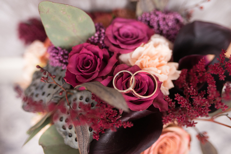 Golden wedding rings lie in a bud of pink rose. Wedding rings lie on a flower budの写真素材