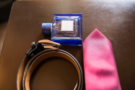 The groom's wedding accessories. Blue perfume in focus, leather belt and red necktie.の写真素材