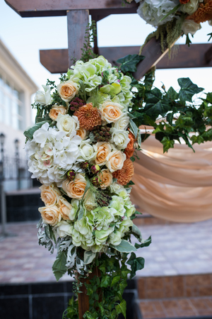 Closeup of beautiful wedding arch with fresh flowers in beige colors in the gardenの写真素材