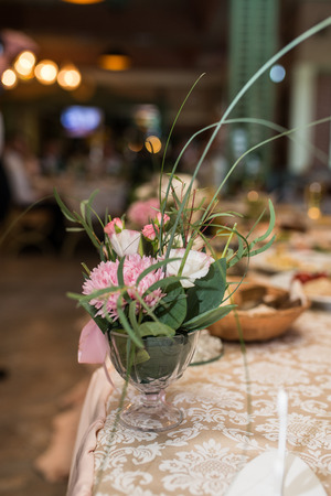 Close up of a rustic flower arrangement with beige flowers and a lot of greenery at a wedding banquet. Rosesの写真素材