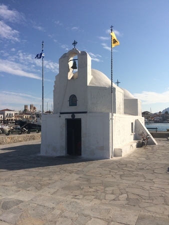 White othodox church, Greece, with a flags. White chapel on a shore.の写真素材