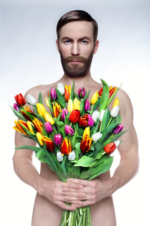 Studio photo naked man with a bouquet of tulips.の写真素材