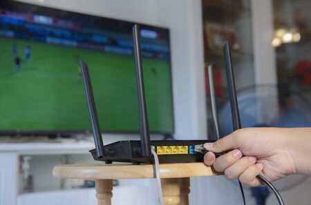 Women hand connects the internet cable to the router's socket