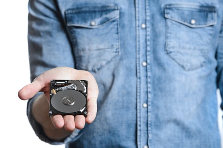 Man's hand holds a 2.5 inch hard drive. He's points to the hard disk. View of the backside HDD, from...