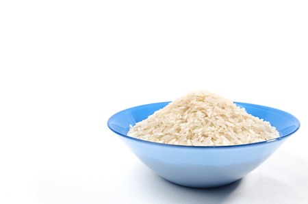 handful of long-grain rice isolated in the blue cup on rightの写真素材