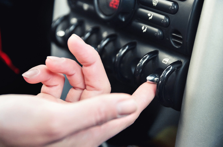 Closeup inside vehicle of button, steering wheel and black interior background, female driver conceptの写真素材