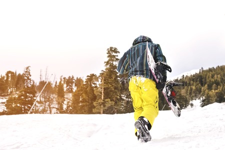 tired snowboarder goes on ski slopeの写真素材