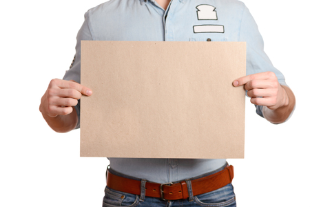 Stylish man in a light denim shirt and dark blue jeans is holding a blank sheetの写真素材