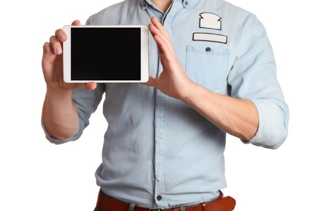 A man in a light blue shirt and jeans with a brown belt is holding tablet pc isolated on white background, pointing to the screen tablet PC, showing all rightの写真素材