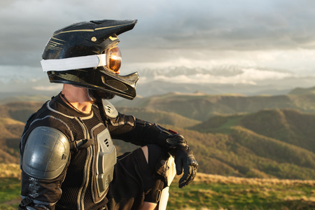 A professional downhill rider sits on a stone resting after a tense race on a mtb bikeの写真素材