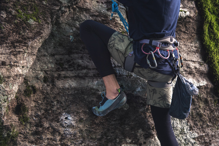 Close-up of a thigh climber with equipment on a belt, stands on a rockの写真素材
