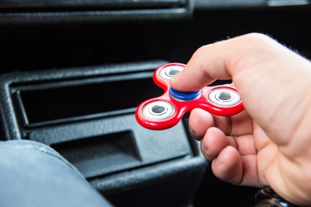 Close-up of a mans hand playing with a spinner while in a traffic jam on the background of the cars interiorの写真素材