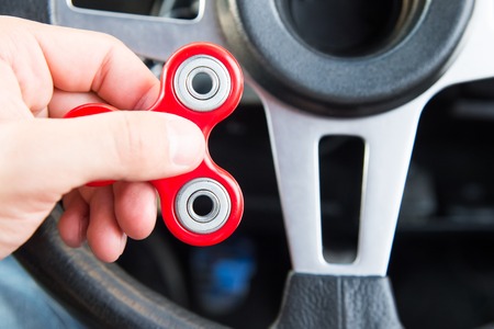 Close-up of a mans hand playing with a spinner while in a traffic jam on the background of the cars interiorの写真素材